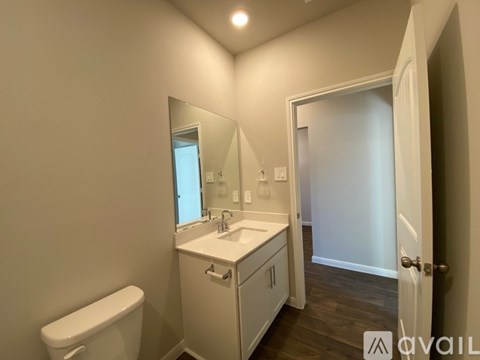 A bathroom with a toilet, sink, and mirror.