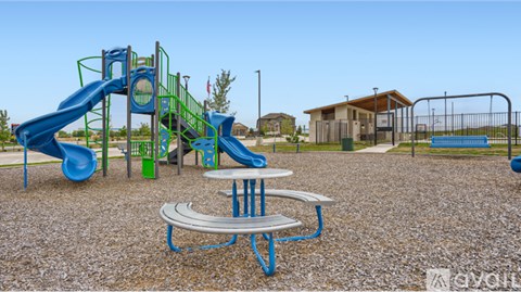 A playground with a blue slide and a picnic table.