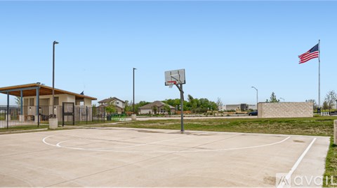 A basketball court with a hoop and a flag on a sunny day.