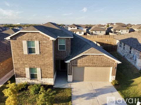 A house with a brown roof and a brown fence with a grassy yard in front.