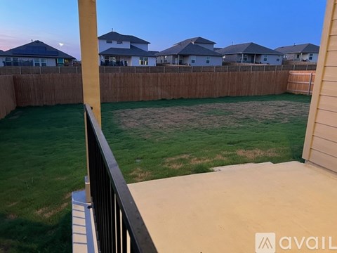 A backyard with a fence and a moon visible in the sky.
