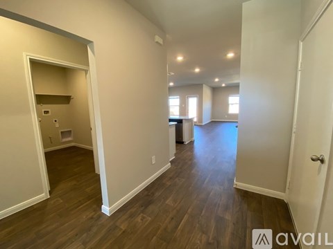 A room with wooden floors and white walls, with a door on the right and a small closet on the left.