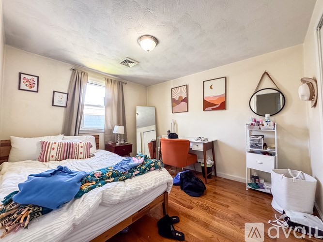 A bedroom with a bed, desk, chair, and a mirror.