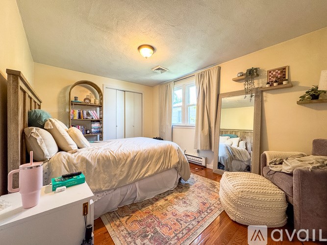 A bedroom with a large bed and a window with curtains.