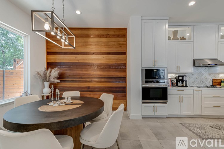 A modern kitchen with a wooden wall and a round dining table.