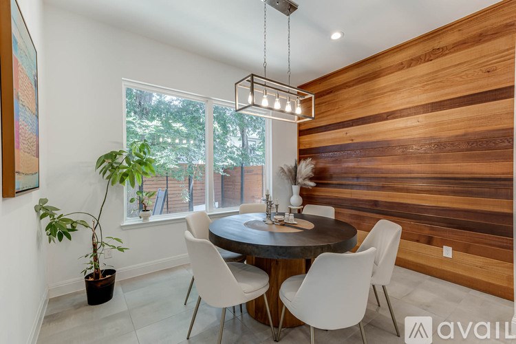 A modern dining room with a round table and white chairs.