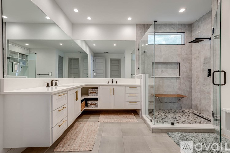 A modern bathroom with a walk-in shower and double sinks.