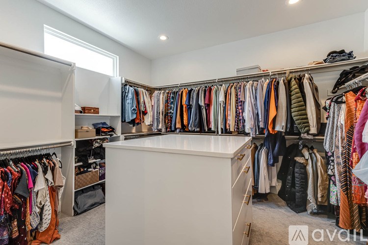 A well-organized walk-in closet with a variety of clothes and shoes.