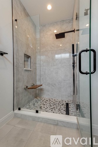 A modern bathroom with a walk-in shower and a glass door.