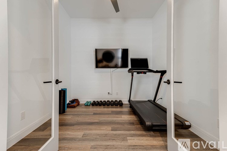 A room with a treadmill, a television and a pair of shoes on the floor.