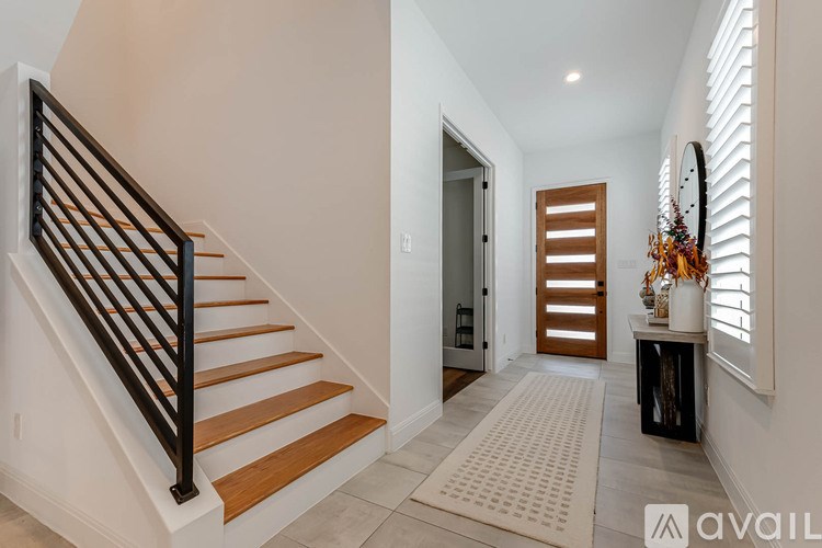 A hallway with a staircase and a door with shutters.
