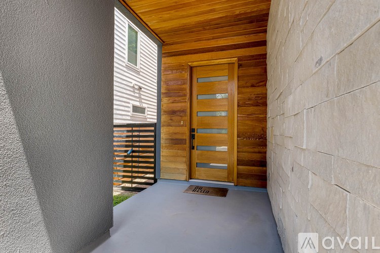 A wooden door with a glass window is in a room with a wooden ceiling and a stone wall.