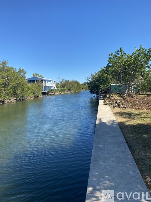 A body of water with a concrete walkway alongside it and a building in the background.