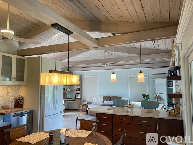 A modern kitchen with wooden ceiling and a dining table set for two.