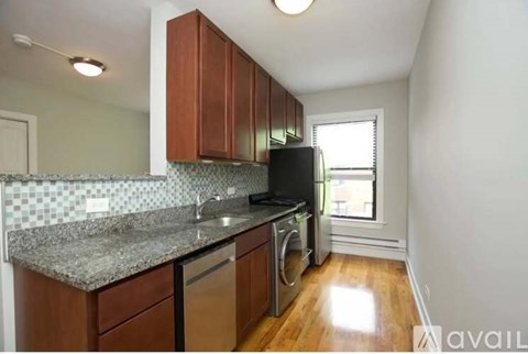 A kitchen with brown cabinets and a black fridge.