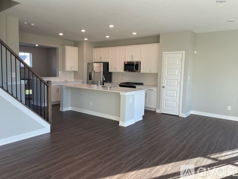 A kitchen with white cabinets and a wooden floor.