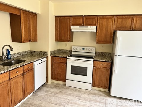 A kitchen with white appliances and wooden cabinets.