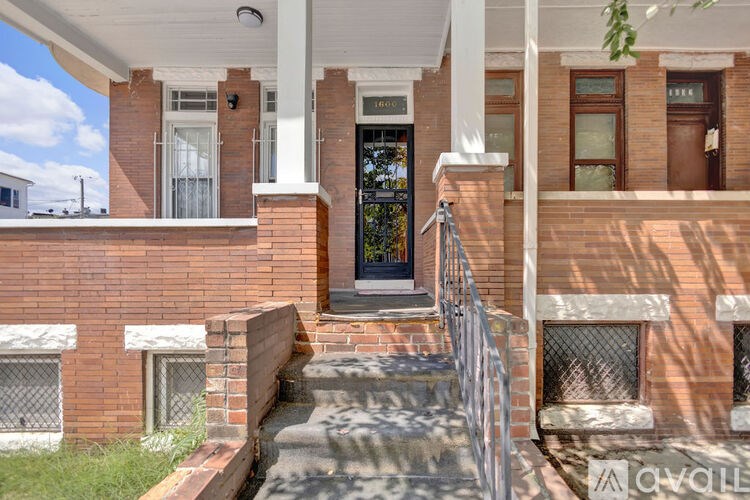 A red brick house with a white porch and a metal railing.