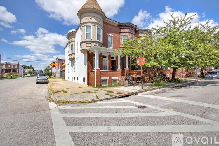 A stop sign is on a street corner with a crosswalk and a building in the background.