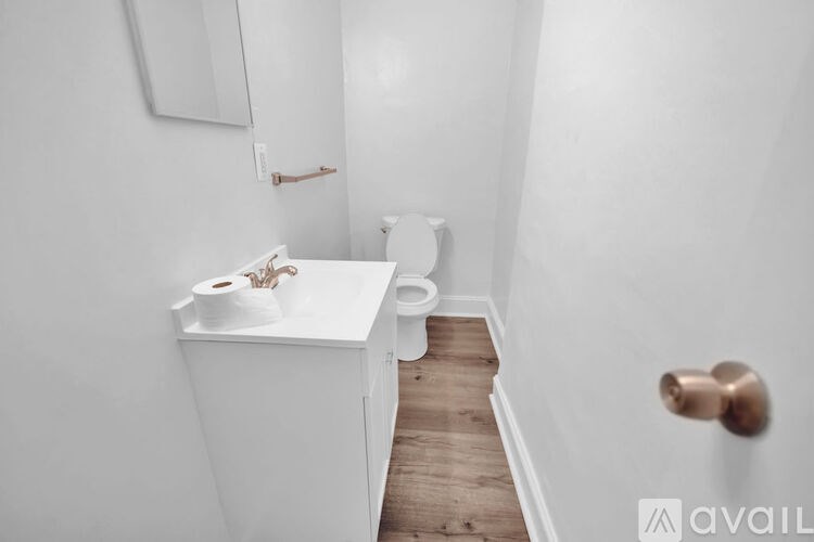 A white bathroom with a toilet, sink, and mirror.