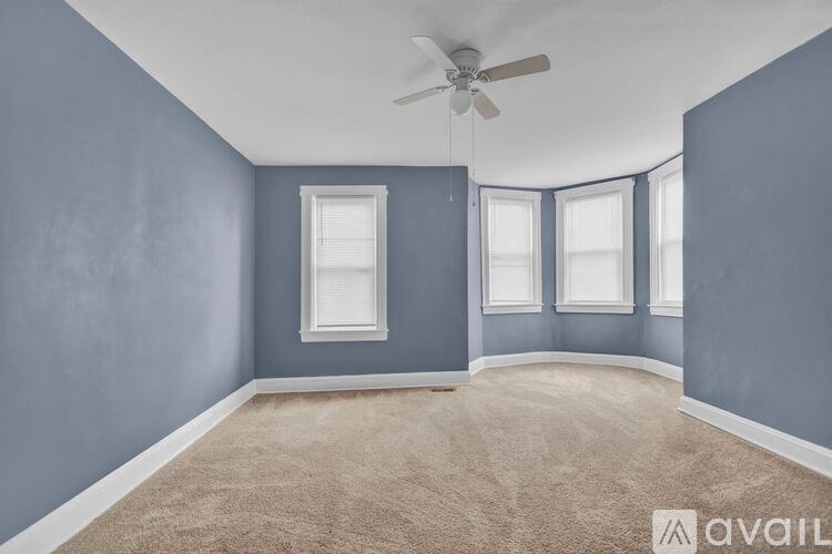 A room with a ceiling fan and three windows.