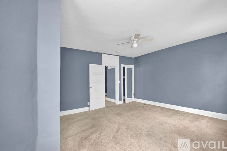 A room with a ceiling fan and a doorway leading to another room.