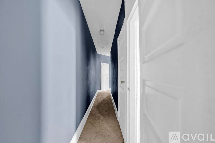 A long hallway with a carpeted floor and white walls.