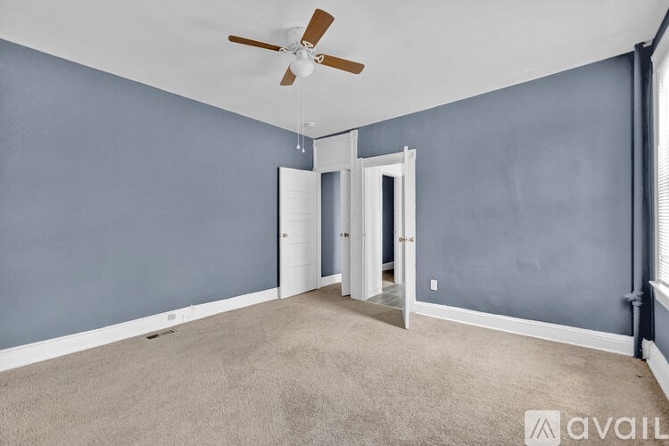 A room with a ceiling fan and carpeted floor.