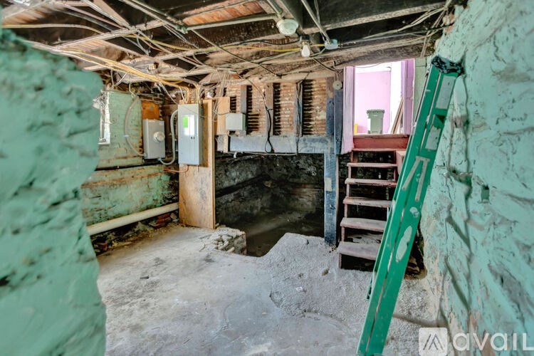 A room with a green ladder and a white electrical box.
