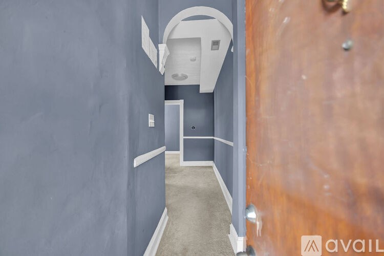 A hallway with a door at the end and a wall on the left.