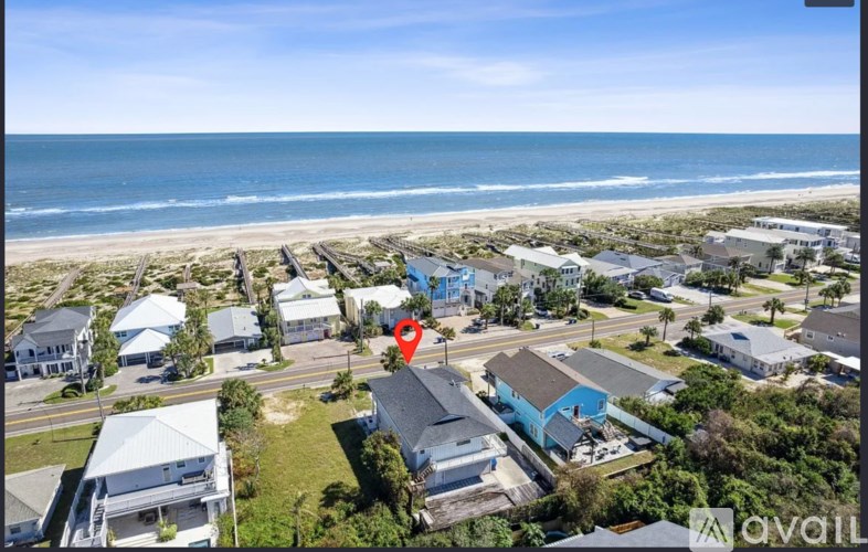 A bird's eye view of a beachfront property with a red marker indicating a specific house.