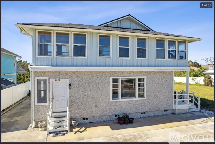 A two-story house with a white exterior and a blue roof.