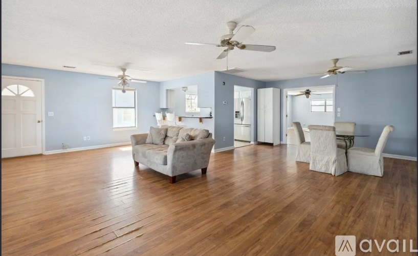 A living room with a couch, chairs, and a ceiling fan.