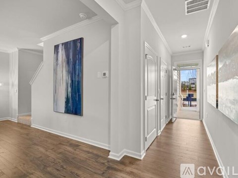 A long hallway with a painting on the wall and a door on the right.