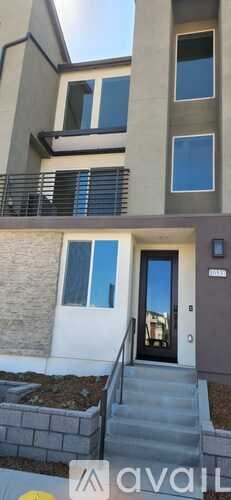A modern two-story building with a balcony and a black door.