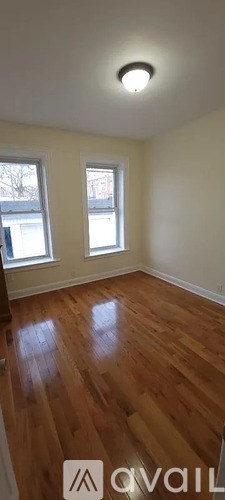 A room with wooden floors and two windows.