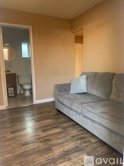 A living room with a grey couch and a wooden floor.