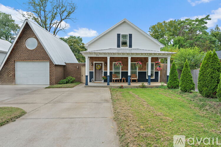 A house with a car parked in front and a sign that says "AVAIL" in the foreground.