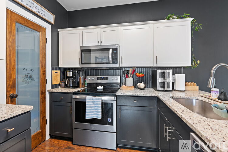 A kitchen with black appliances and white cabinets.