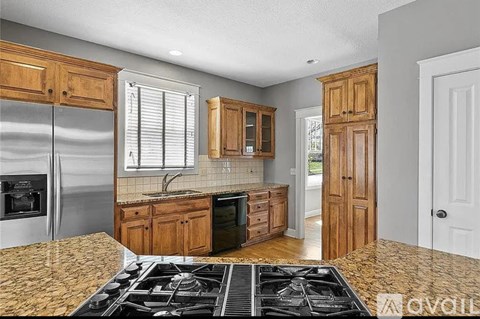 A kitchen with a stove top oven and wooden cabinets.