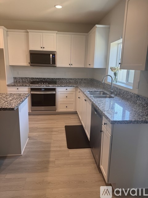 A kitchen with white cabinets and a granite countertop.