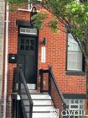 A brick building with a black door and steps leading up to it.