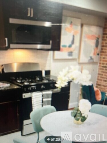 A kitchen with a stove and a table with a vase of flowers on it.