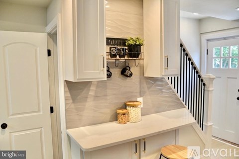A kitchen with white cabinets and a countertop with jars and plants.