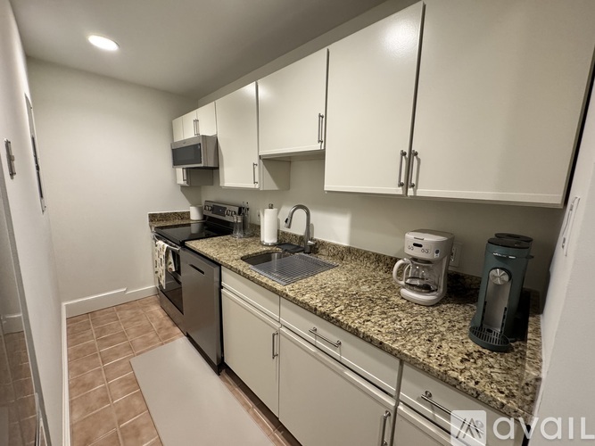 A kitchen with a stainless steel refrigerator and white cabinets.