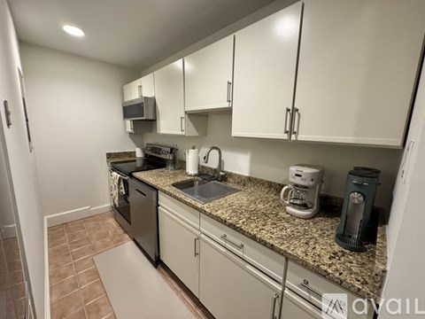 A kitchen with a stainless steel refrigerator and white cabinets.