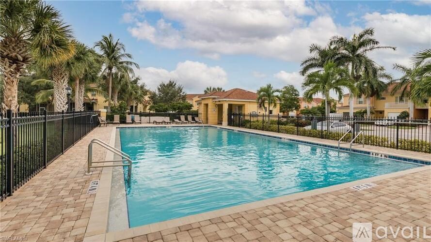 A swimming pool surrounded by palm trees and a fence.