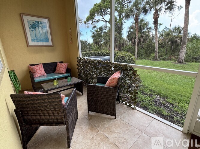 A patio with a table and chairs overlooking a grassy area.