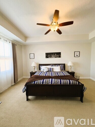 A bedroom with a large bed and a ceiling fan.