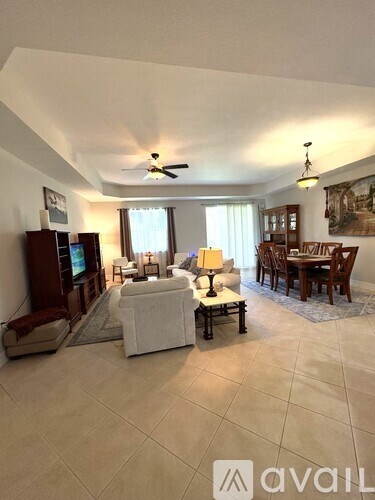 A living room with a television, couch, and chairs.